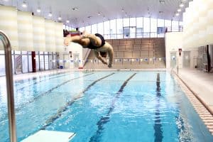 Sportler springt vom 1-Meter Brett ins Wasser des hochschuleigenen Schwimmbads