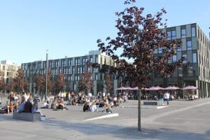 Studierende sitzen vor dem Hauptgebäude der Hochschule Bielefeld am Standort Bielefeld in der Sonne.