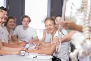 Gruppe Studierende mit lächelnder Frau im Vordergrund vor Anatomiemodell