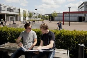 Zwei Studierende betrachten gemeinsam ein Buch auf dem Campus